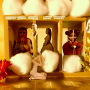 A box surrounded by cotton balls and flowers, there are three images of women in the box, and the words 'Beyond the Lowland every light Sleepless burning ash'