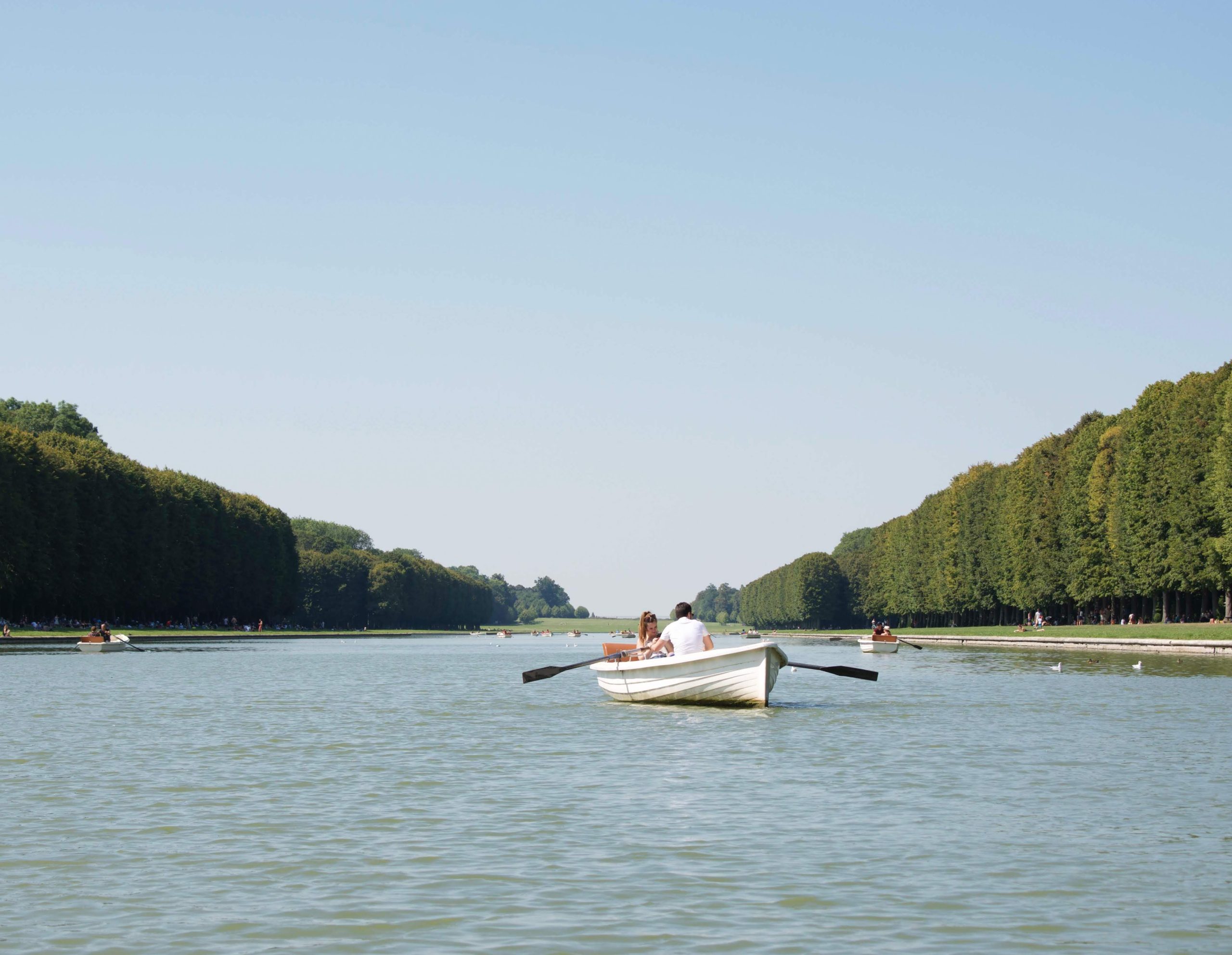 A man and woman in a white rowboat on a lake