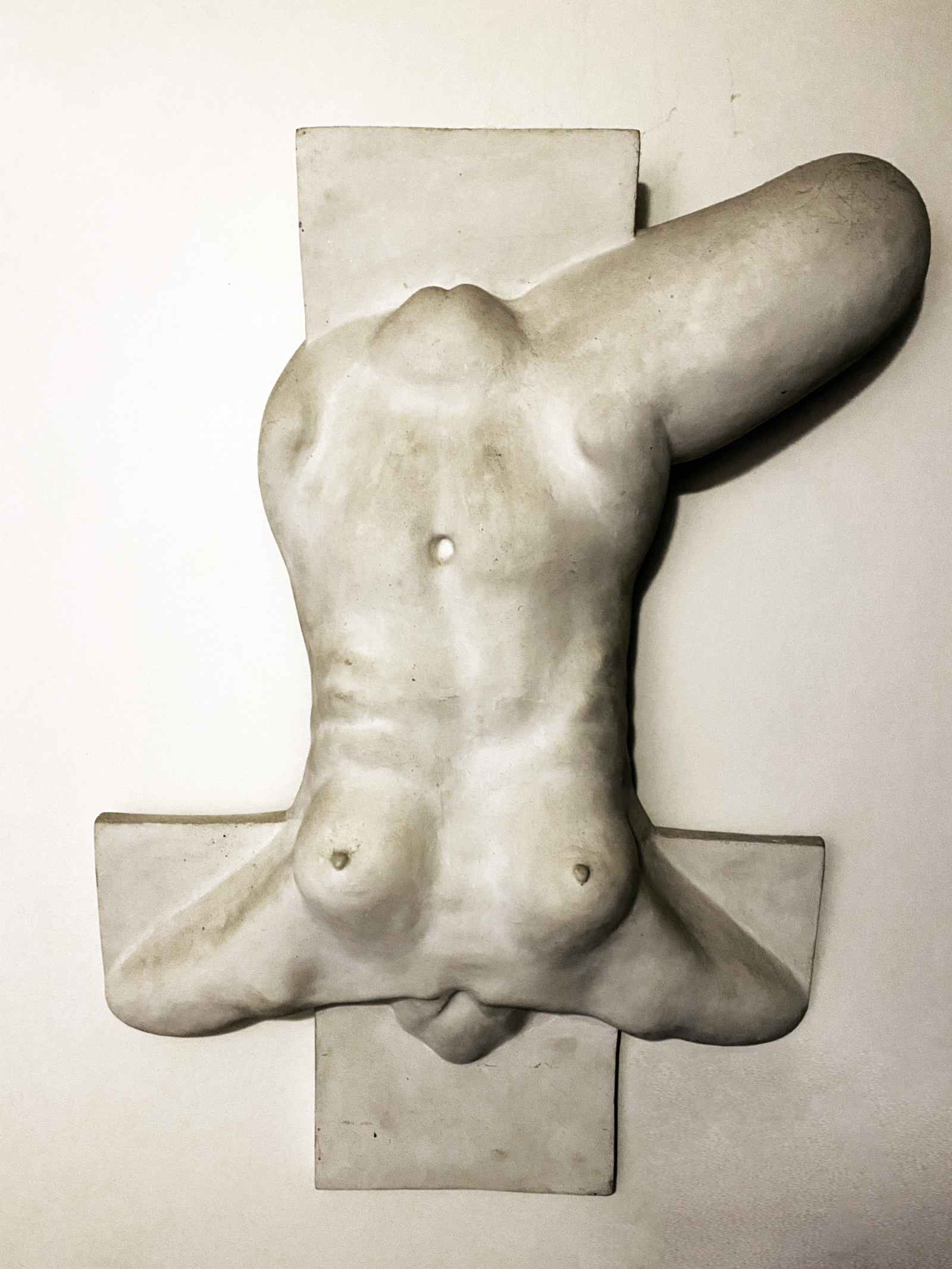 Photo of a grey sculpture of a body, upside down, with one leg bent at the top right