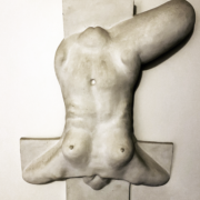 Photo of a grey sculpture of a body, upside down, with one leg bent at the top right