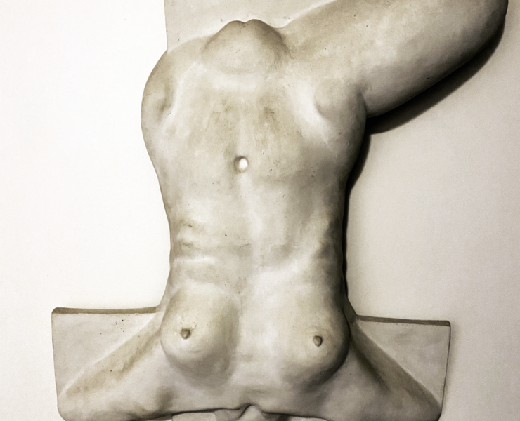 Photo of a grey sculpture of a body, upside down, with one leg bent at the top right