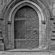 Black and white photo of a church door with tree designs on the hinges