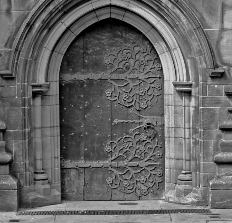 Black and white photo of a church door with tree designs on the hinges