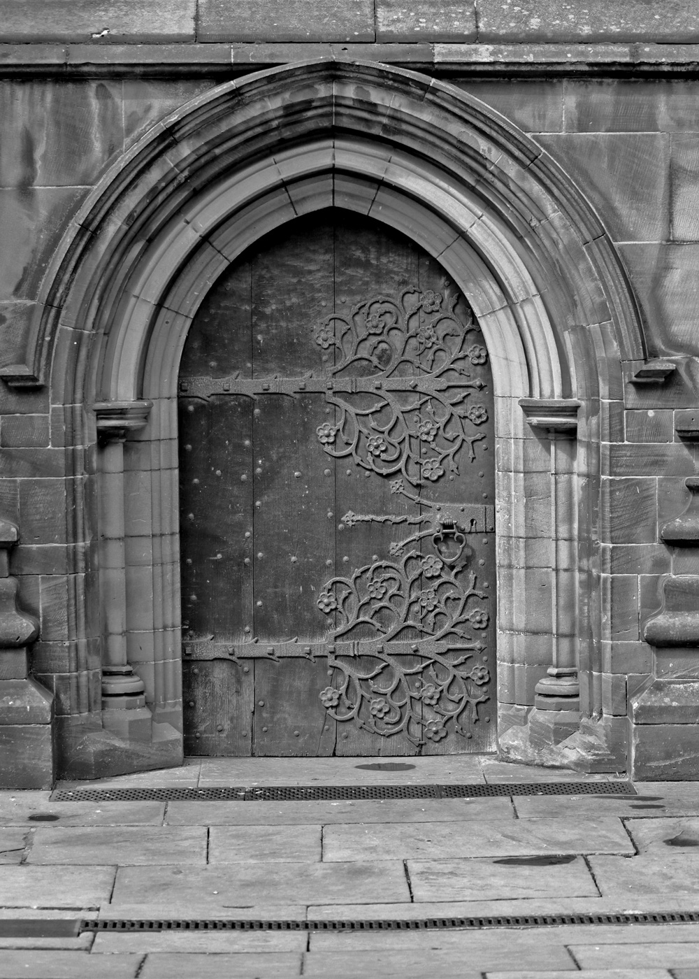 Black and white photo of a church door with tree designs on the hinges