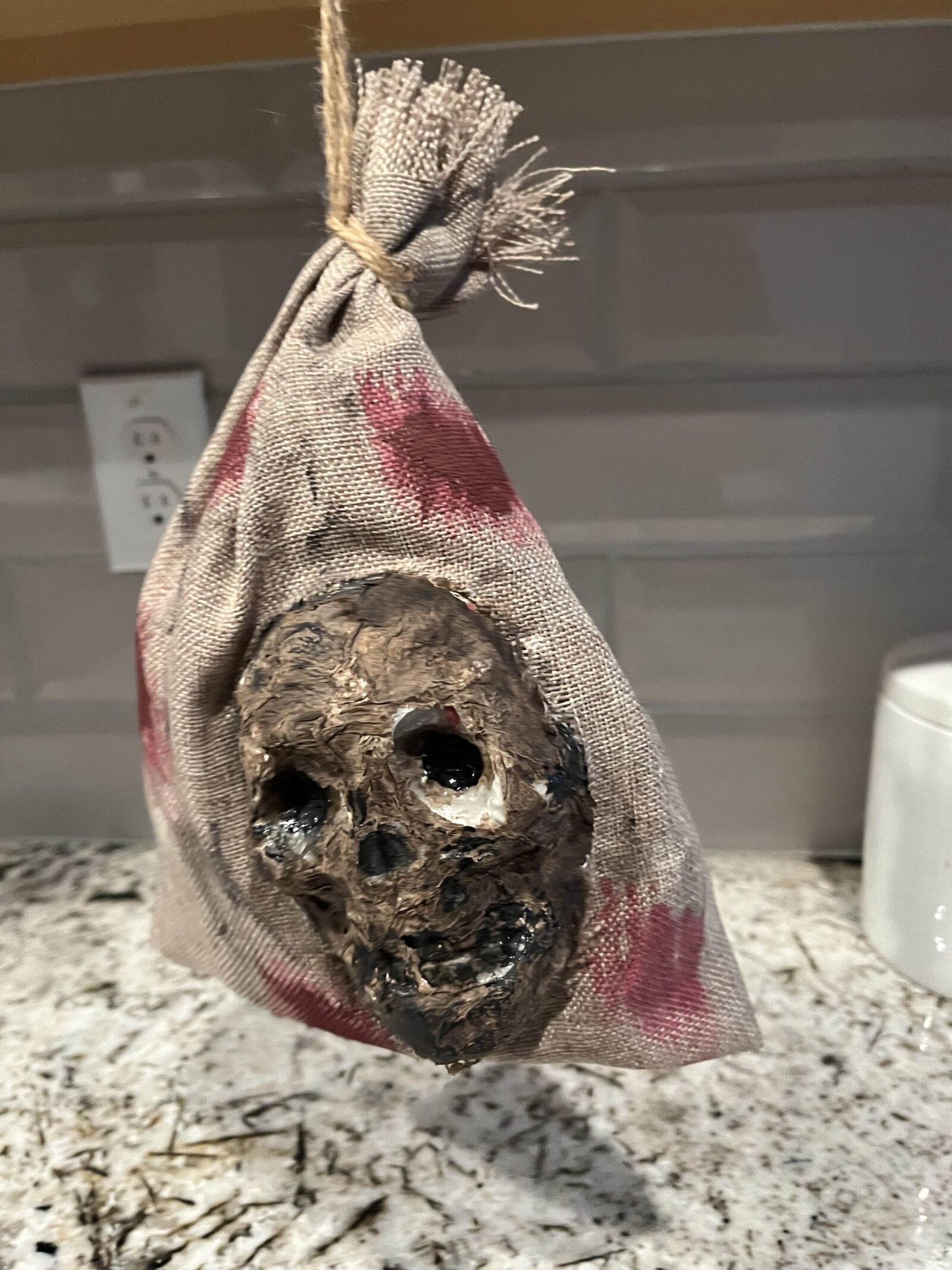 Halloween prop of a zombified skull in a bloody burlap sack
