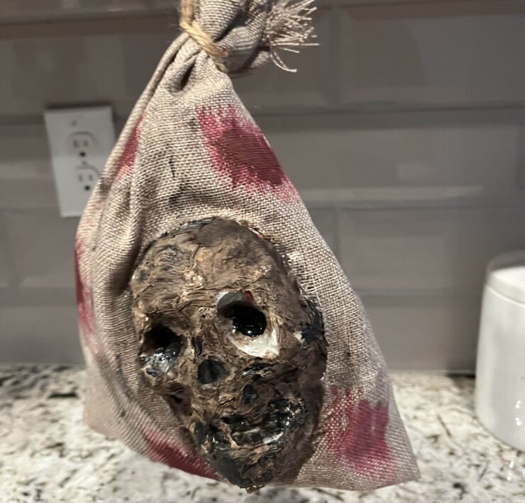 Halloween prop of a zombified skull in a bloody burlap sack