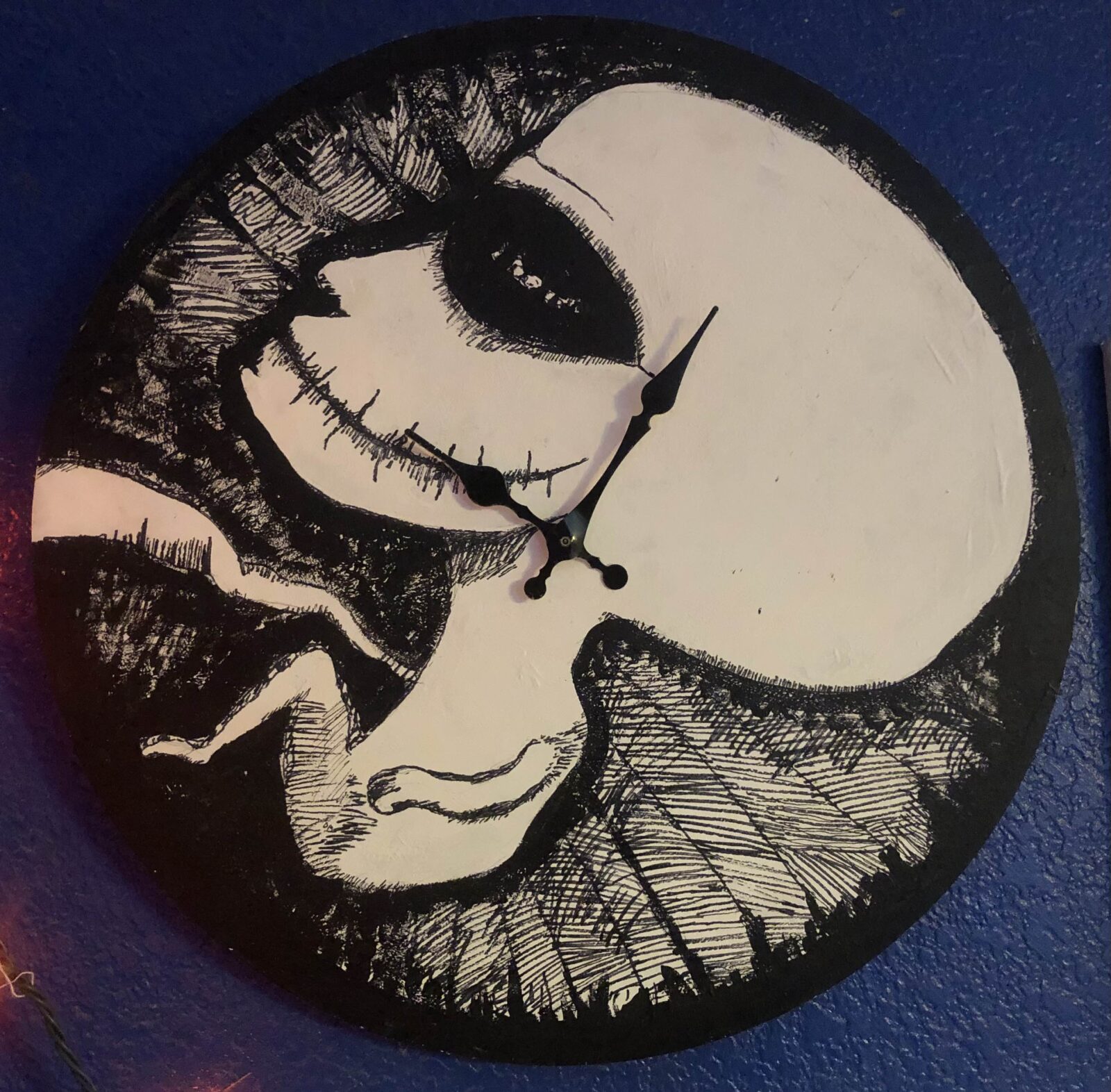 A fetus with an adult head painted in black and white on a clock